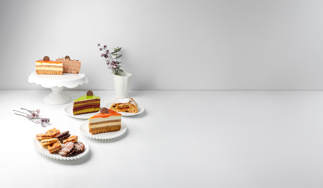 Los trozos de tartas y pasteles se colocan en platos blancos y un soporte para tartas, con un pequeño jarrón de flores al fondo, todo ello sobre un fondo blanco minimalista.